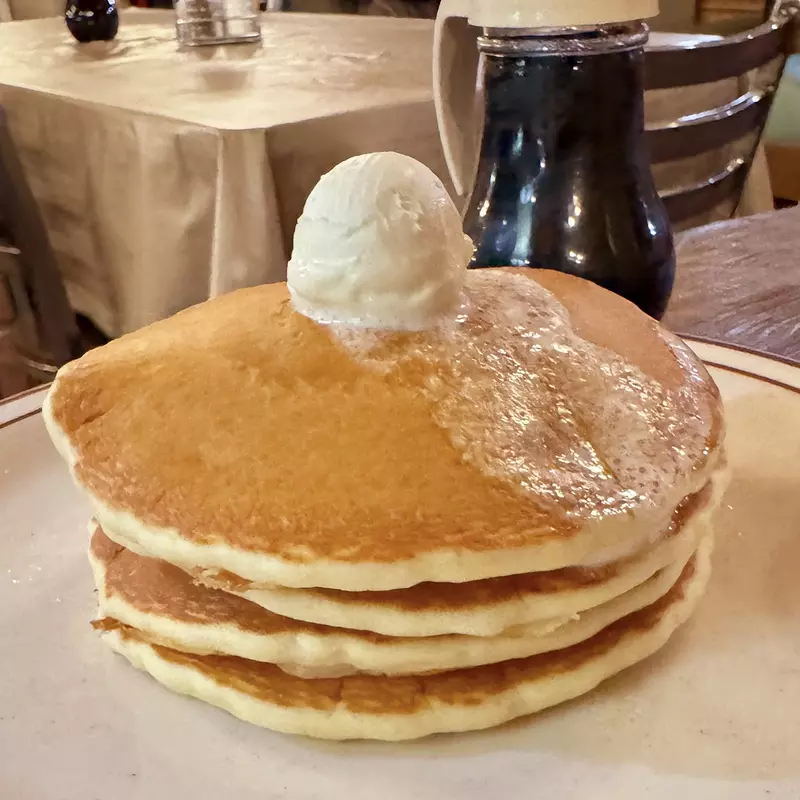 pouring syrup on stack of pancakes