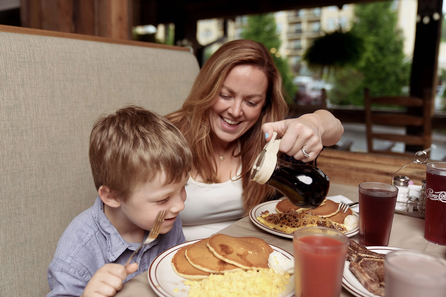 mother pouring syrup on her son's pancakes