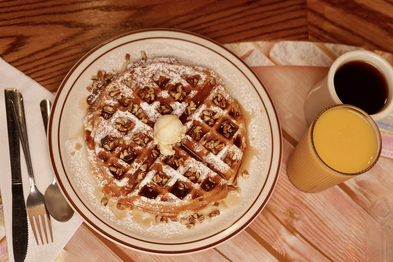 waffle with syrup and a cup of coffee with orange juice